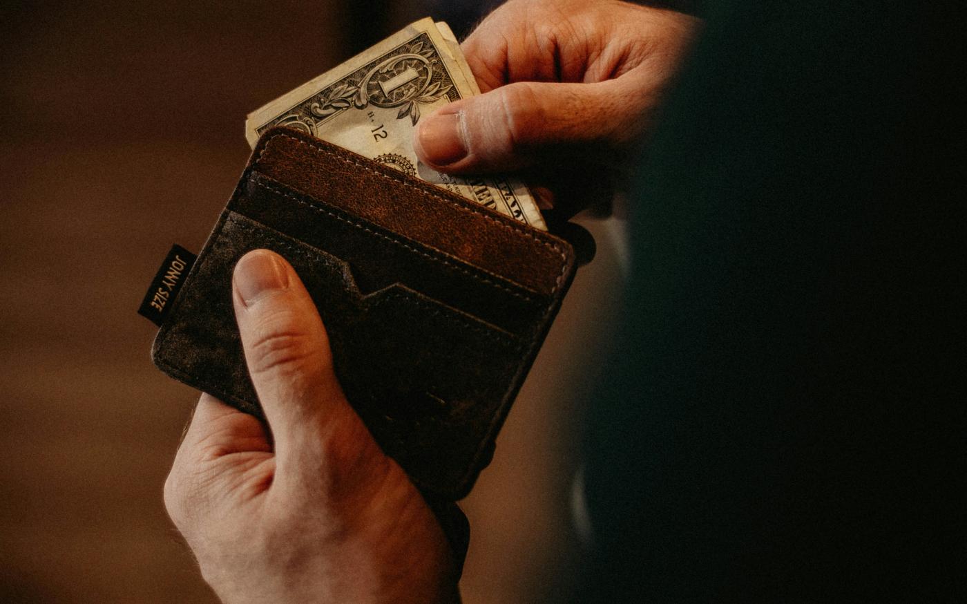 person getting 1 U.S. dollar banknote in wallet by Allef Vinicius courtesy of Unsplash.