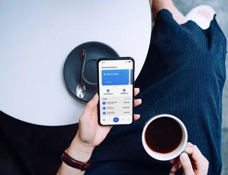 a person holding a phone and a cup of coffee