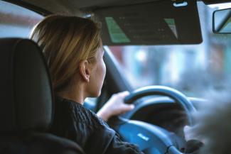 a woman sitting in a car with a steering wheel by Jan Baborák courtesy of Unsplash.