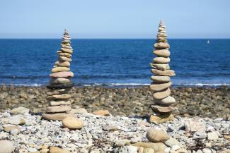 a pile of rocks sitting on top of a rocky beach by Dave Lowe courtesy of Unsplash.