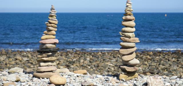 a pile of rocks sitting on top of a rocky beach by Dave Lowe courtesy of Unsplash.