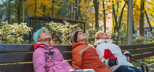 three people sitting on a bench in a park by Vitolda Klein courtesy of Unsplash.